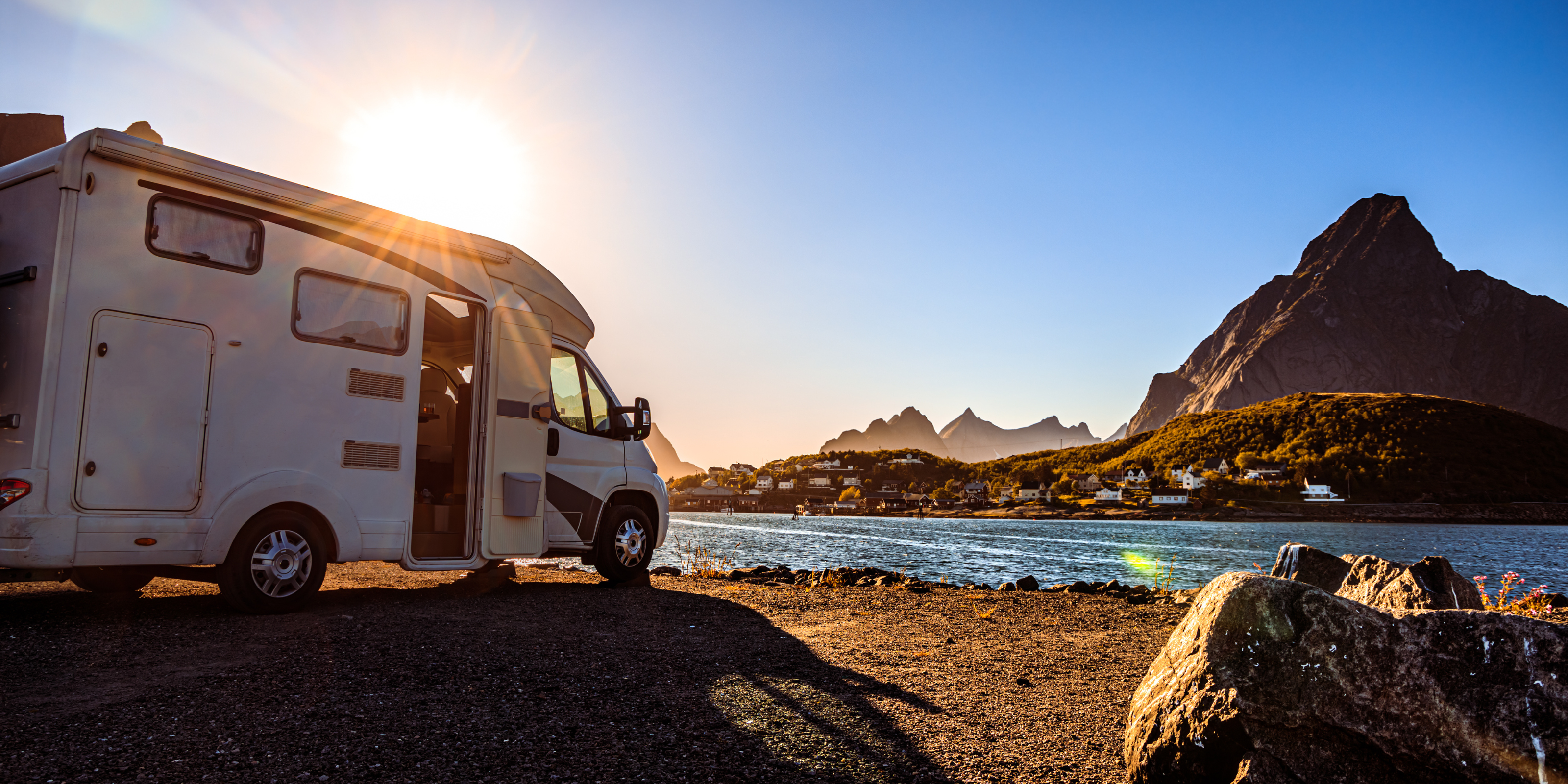 Ein Wohnmobil am See bei Sonnenschein.