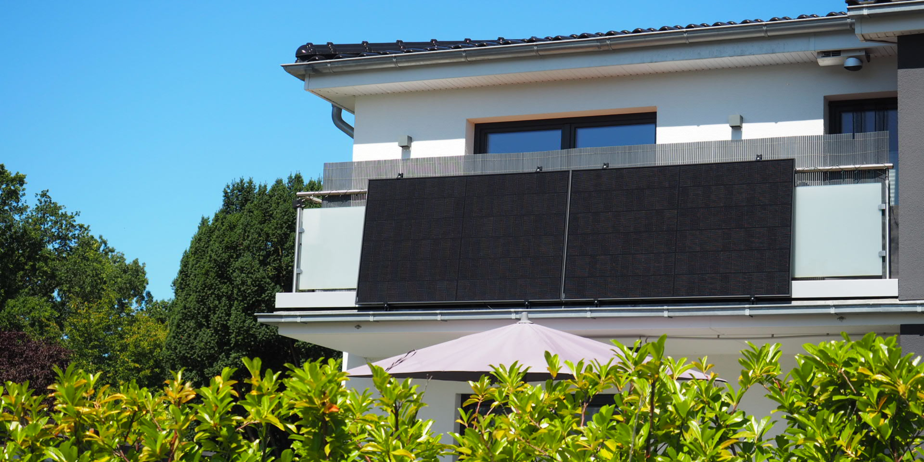 An einem Balkongeländer sind zwei Solarmodule montiert.