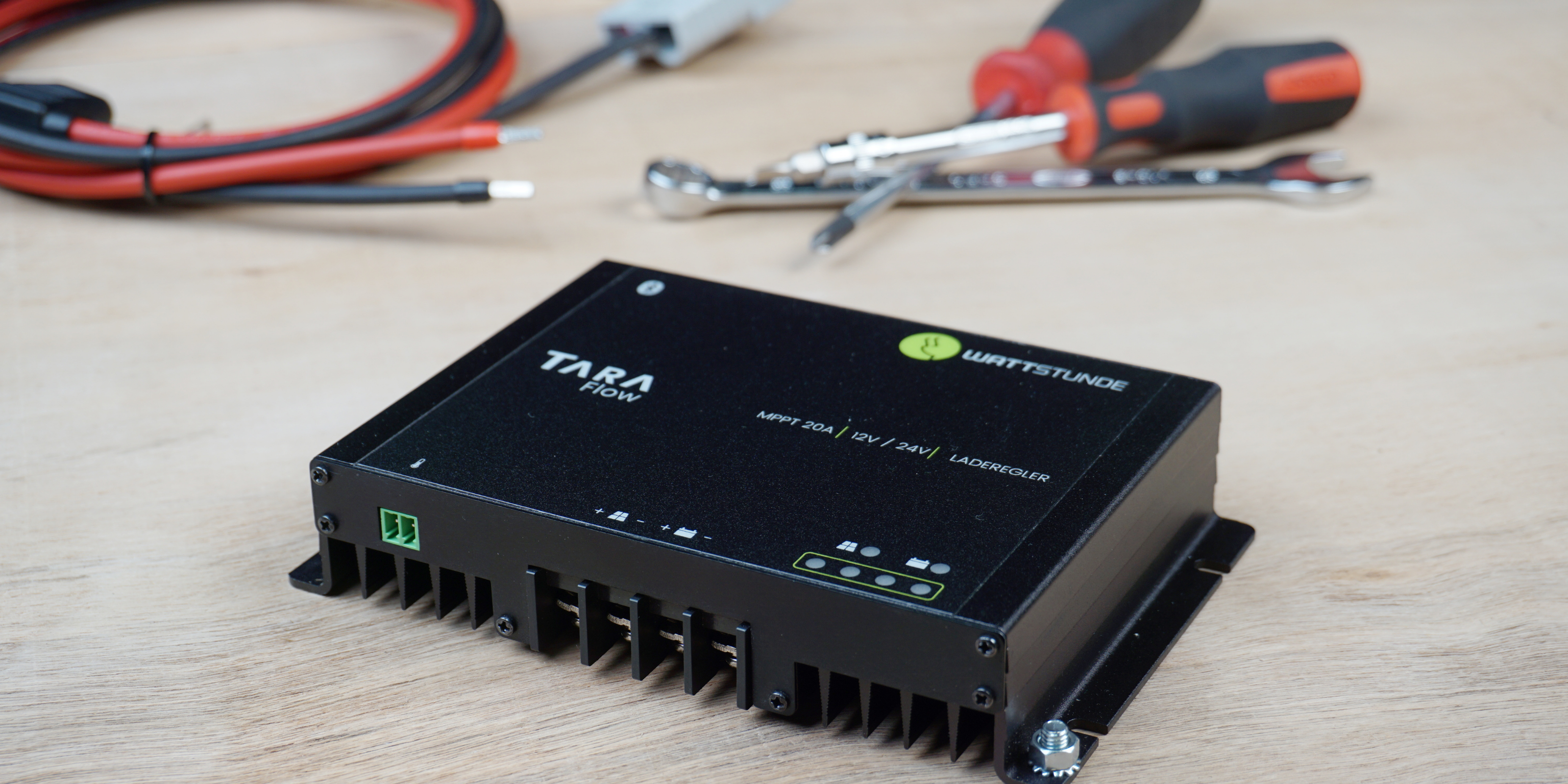 Der Laderegler von WATTSTUNDE TARA Flow liegt auf einem Tisch mit einem Solarkabel und Werkzeug.