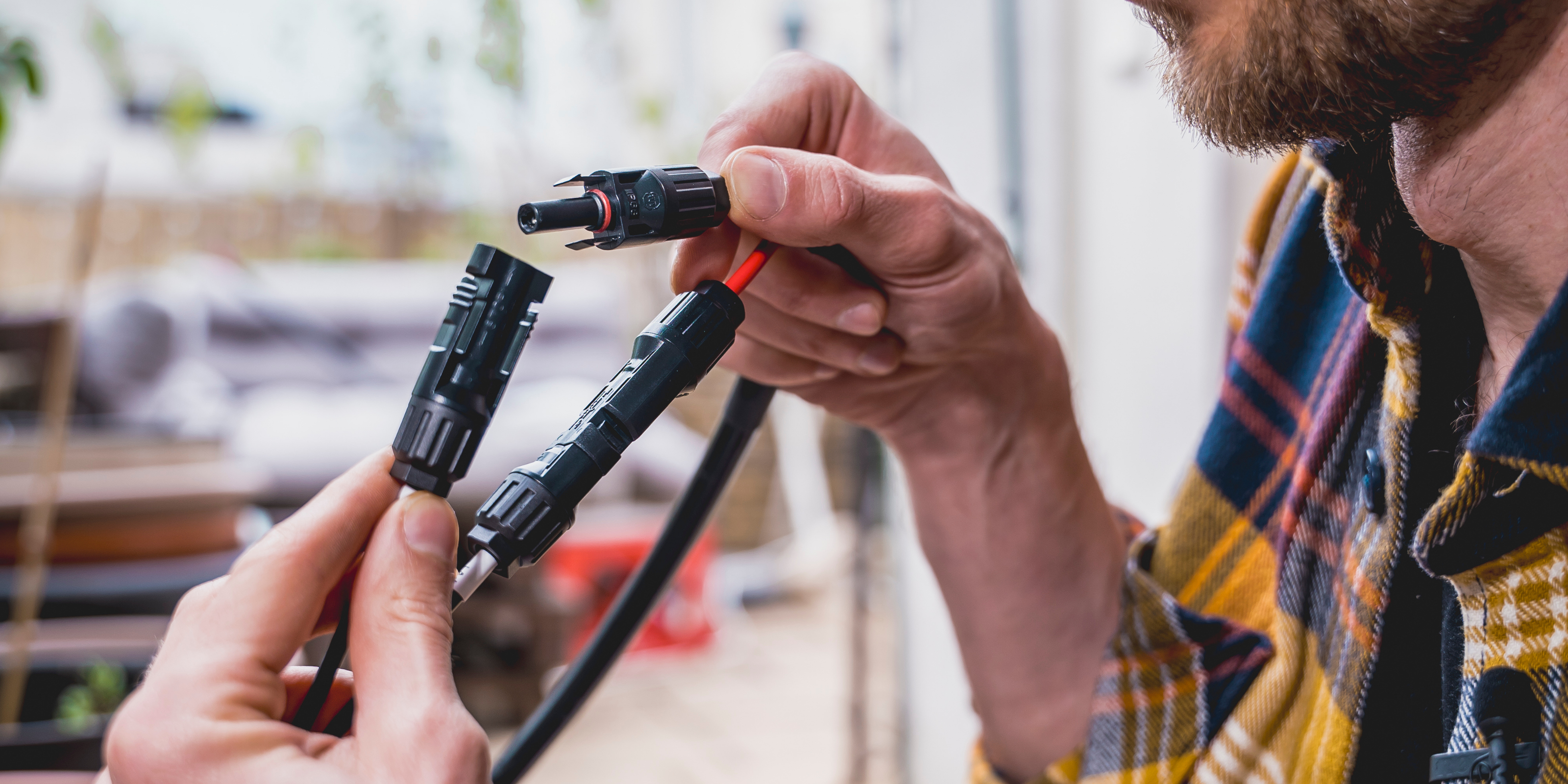 Ein Mann schließt zwei Solarkabel zusammen.