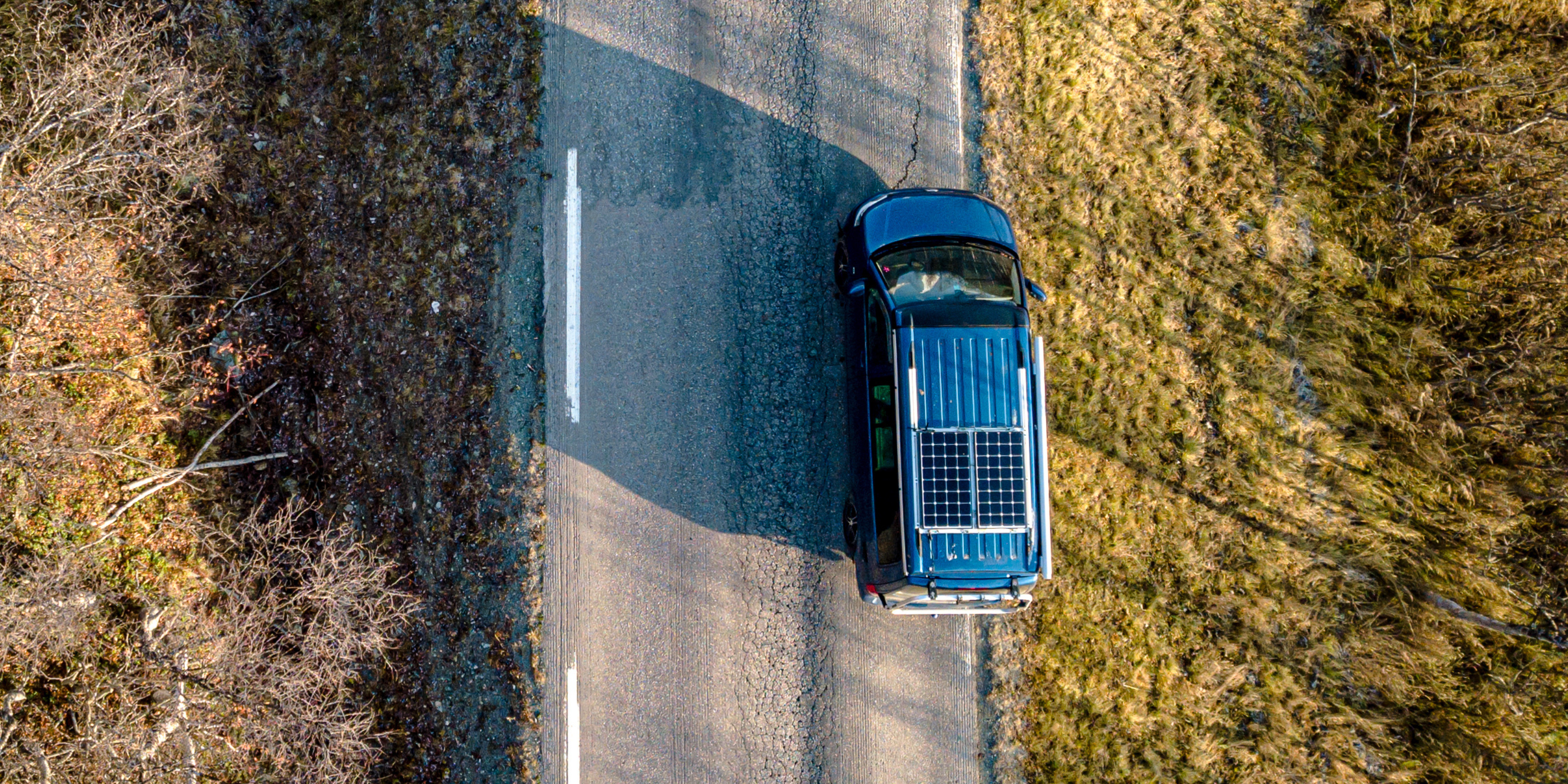 Ansicht einer Drohne über ein Einsatzfahrzeug, das über eine Landstraße fährt.