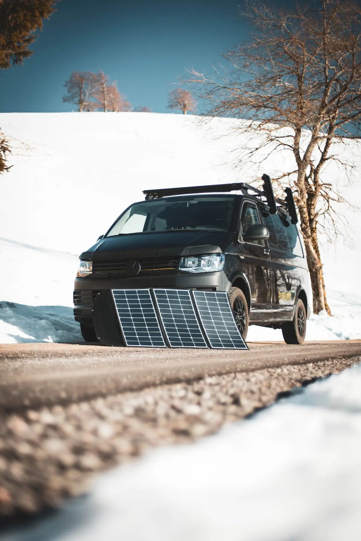 Ein Wohnmobil in eine verschneite Landschaft. Davor eine Solartasche, die zum Laden von Solarenergie dient.