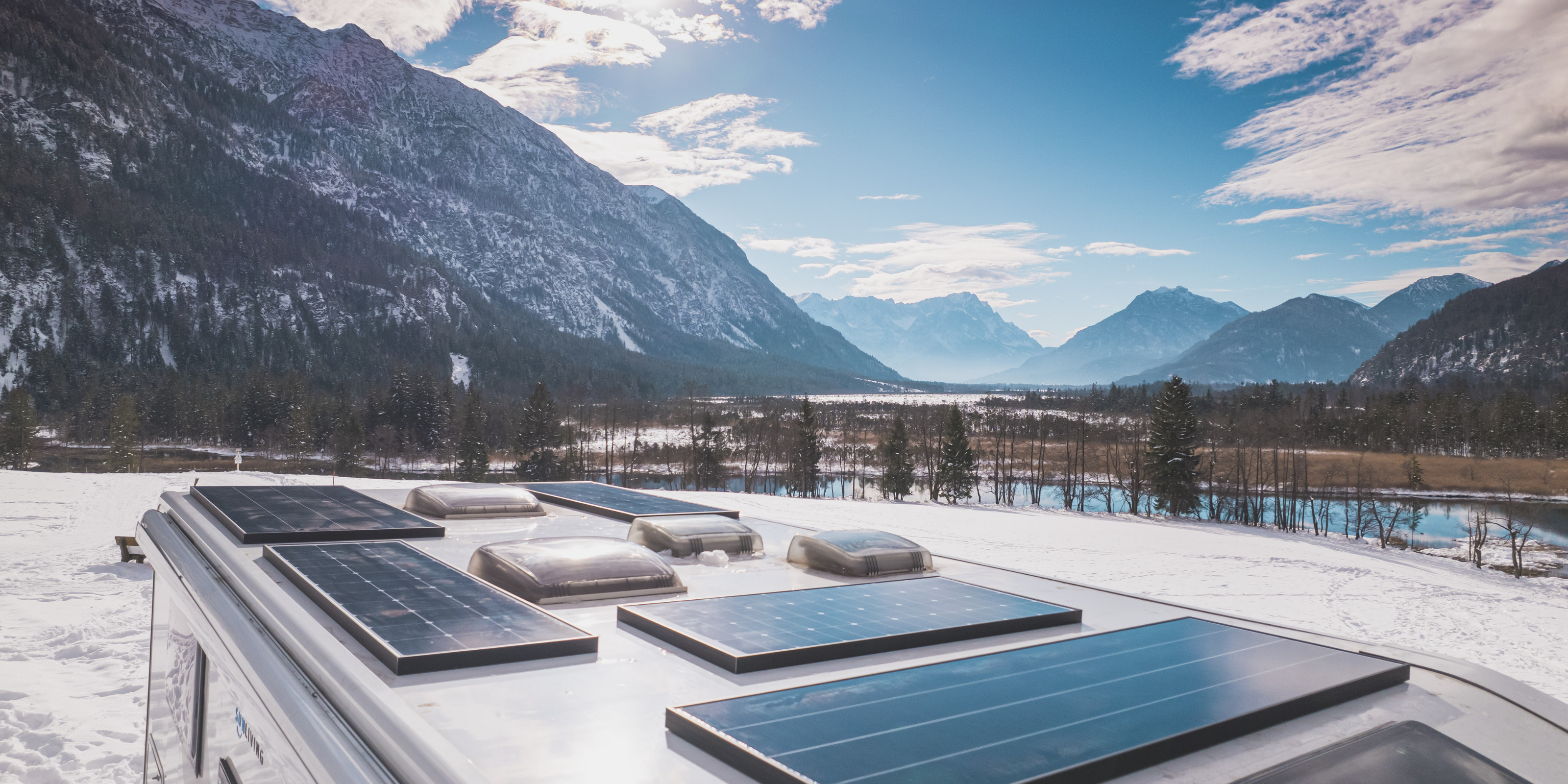 Solarmodule sind auf dem Dach eines Reisefahrzeuges verbaut, welches in den Bergen steht.