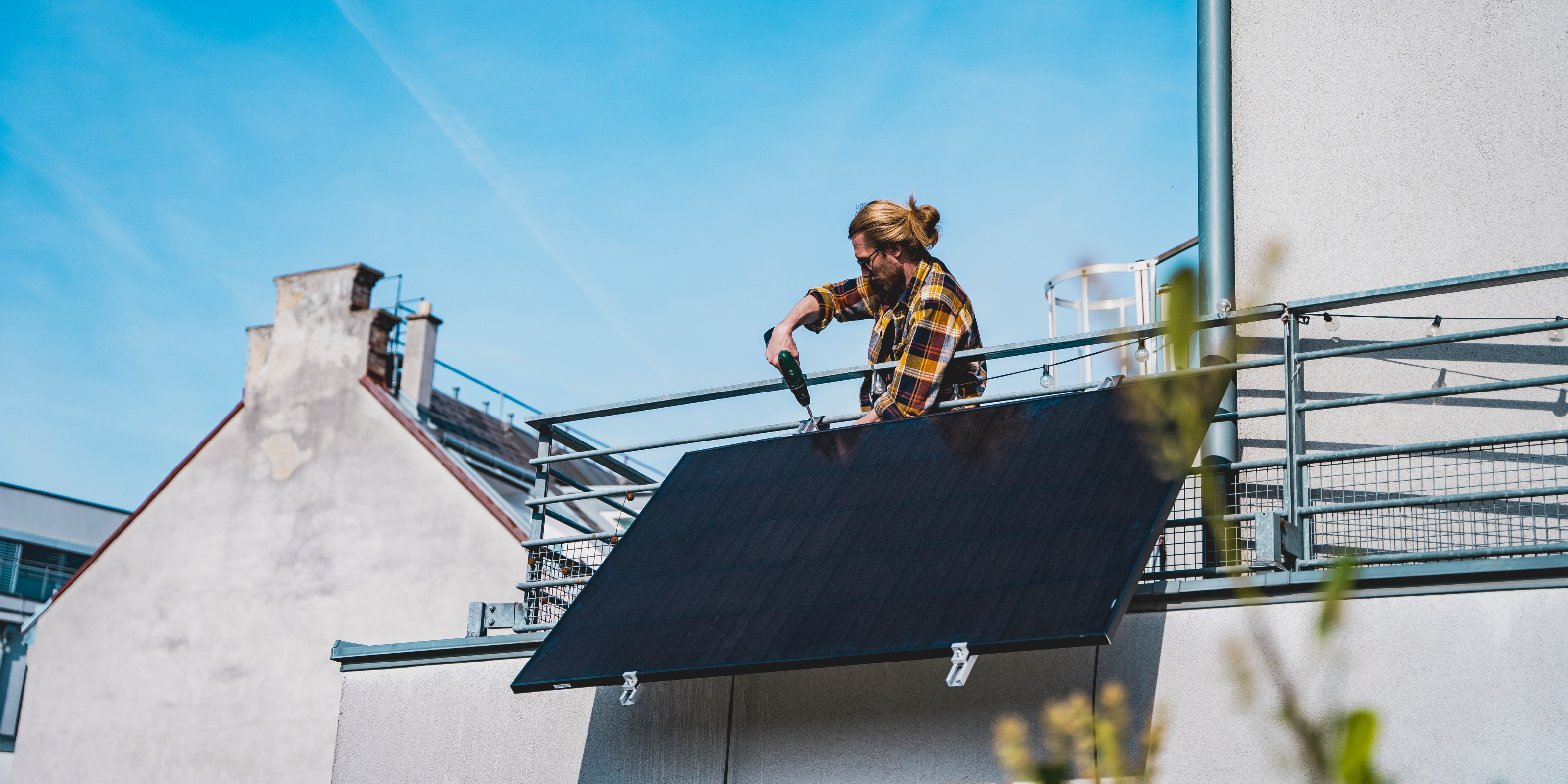 Eine Person baut ein Balkonkraftwerk auf dem Balkon an.