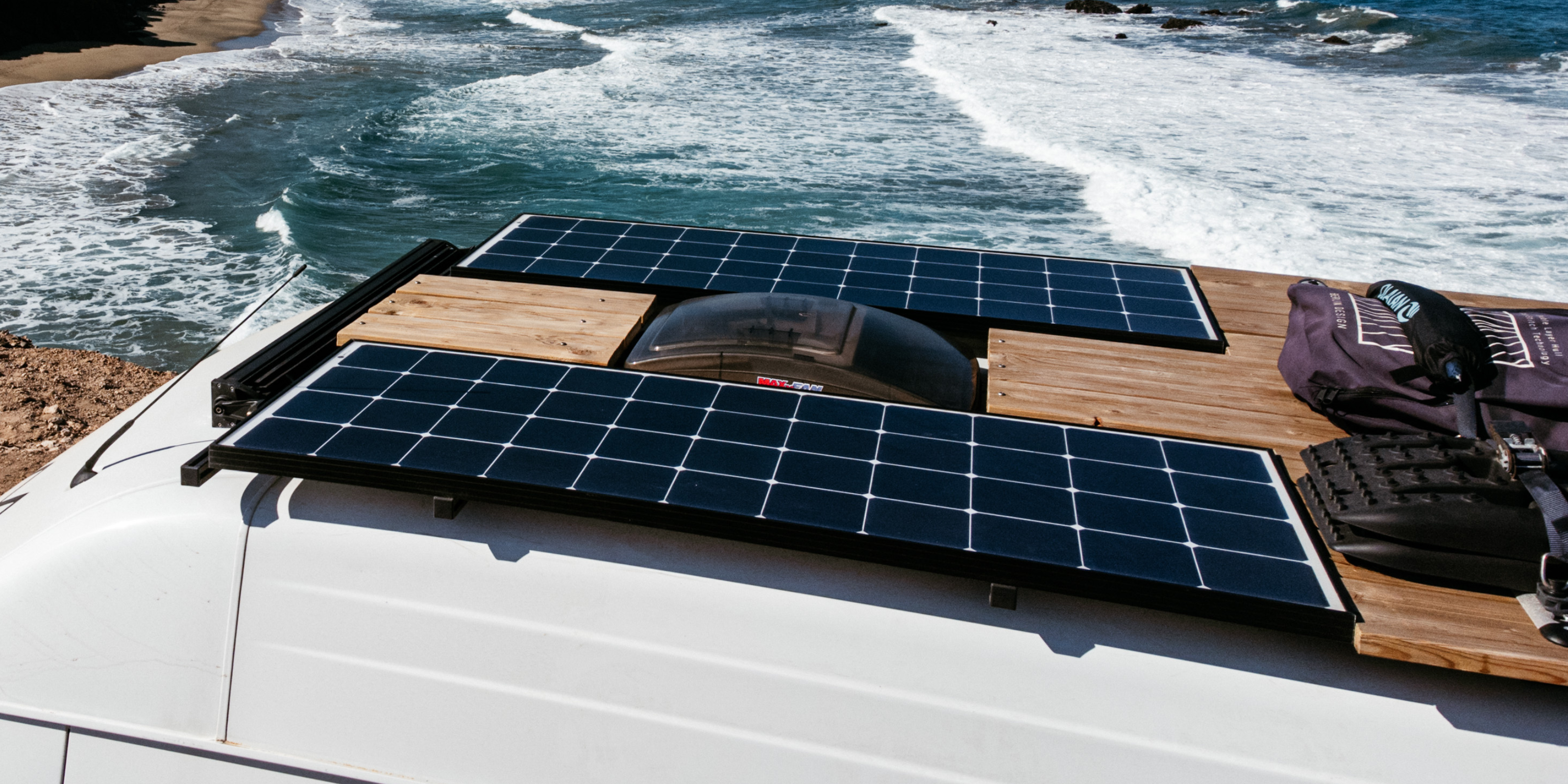 Am Meeresrand steht ein Wohnmobil, bestückt mit einer Solaranlage. Im Hintergrund der Horizont.