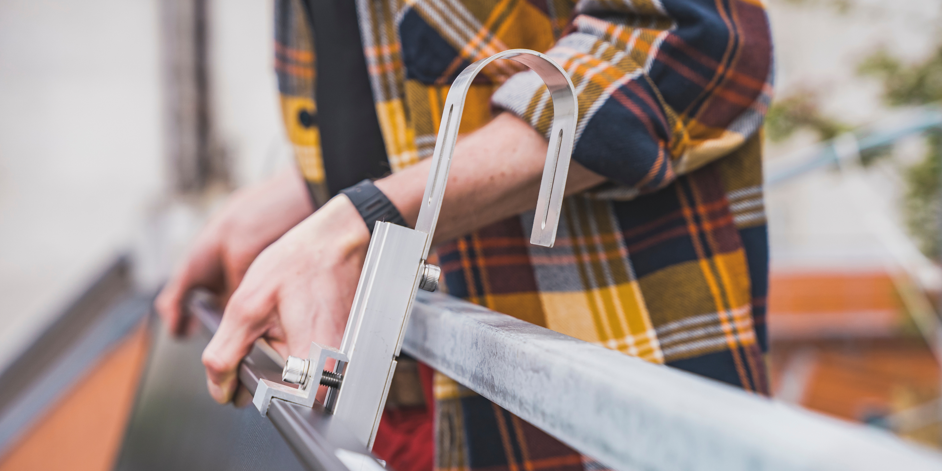 Ein Mann hängt ein Solarmodule an den Balkon.