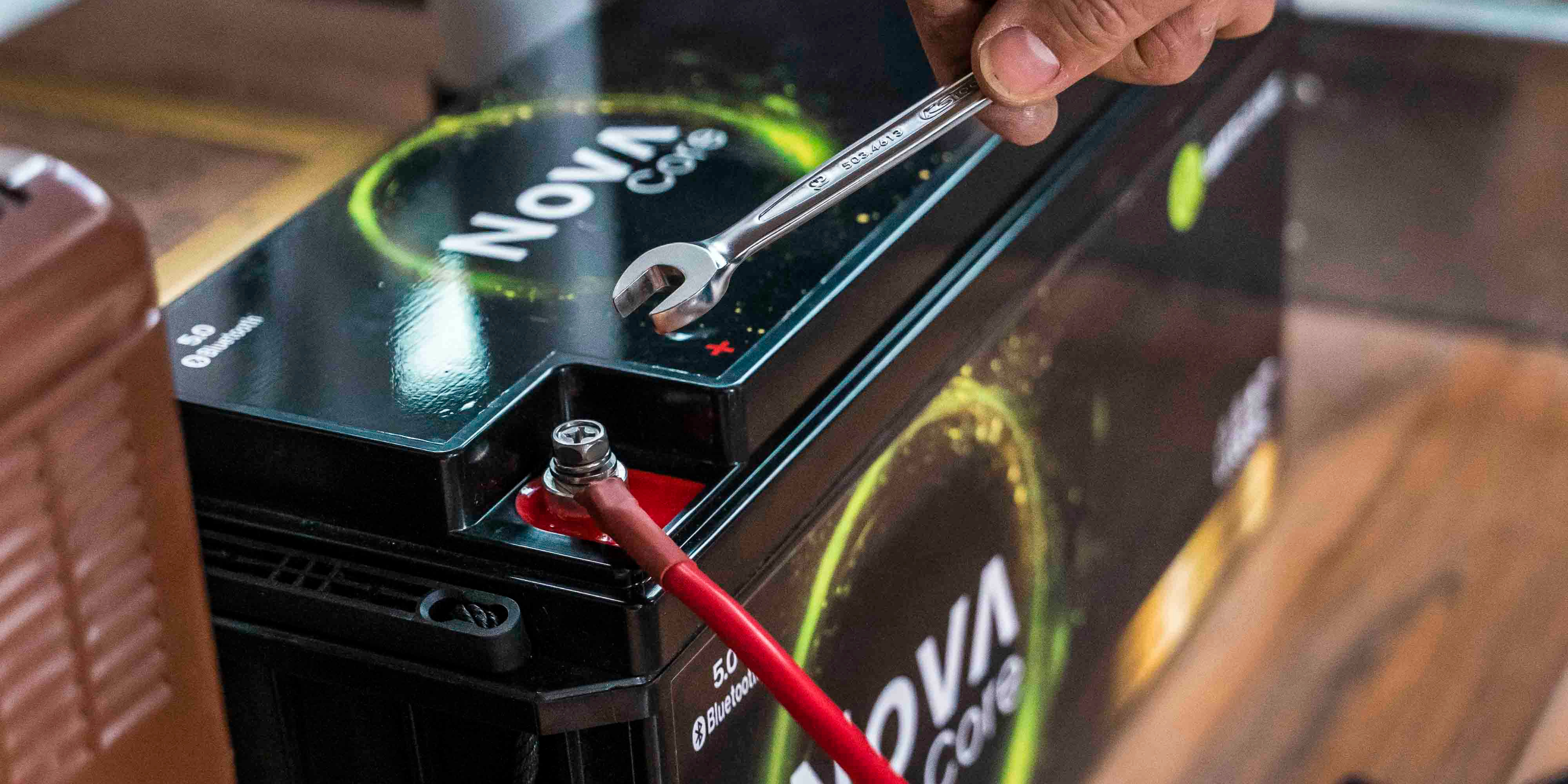 Die Kabel einer Lithiumbatterie von WATTSTUNDE werden mit einem Werkzeug festgeschraubt.