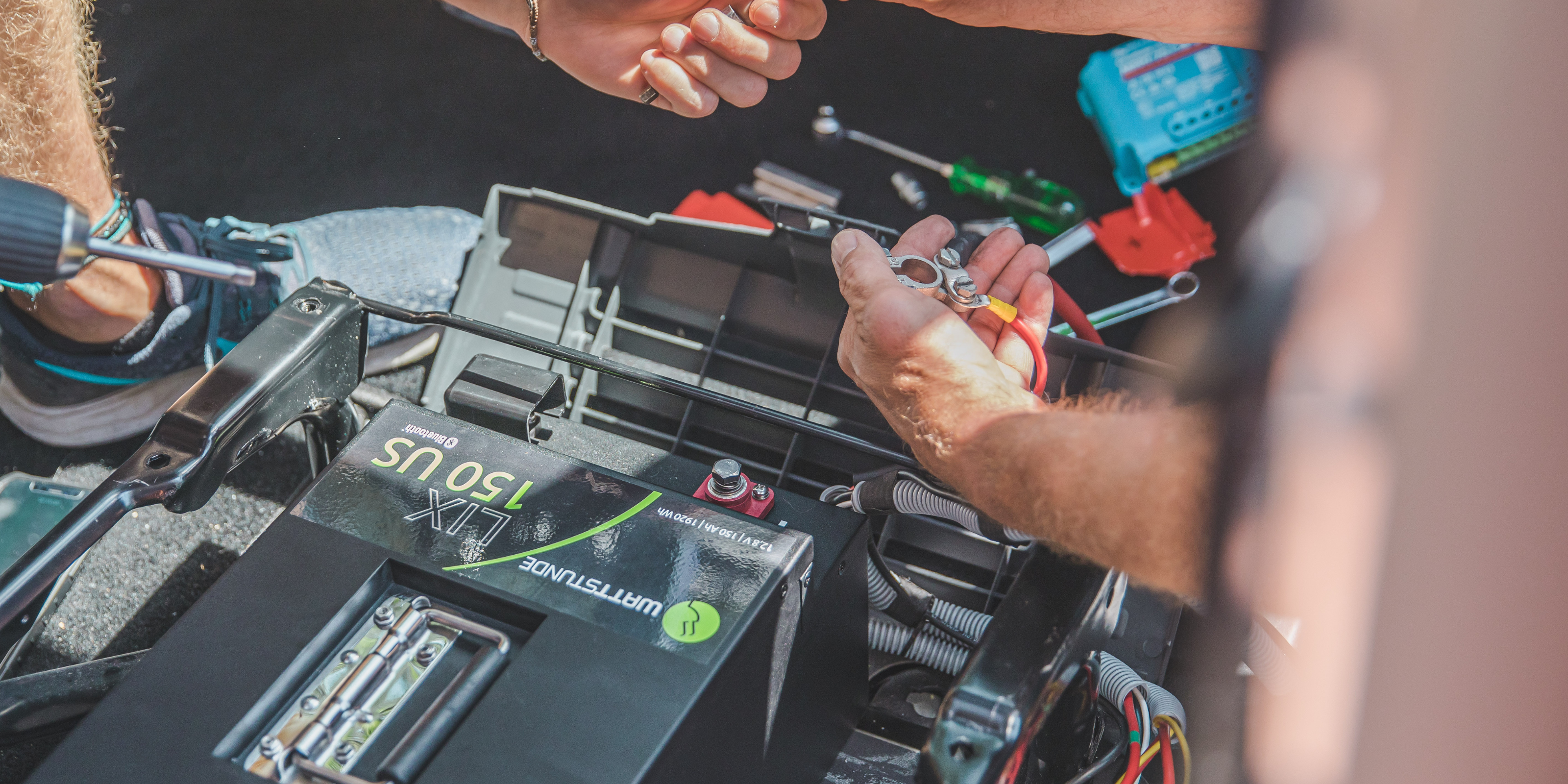 Einbau einer Batterie im Motorraum eines Campers - darunter Sicherungen.